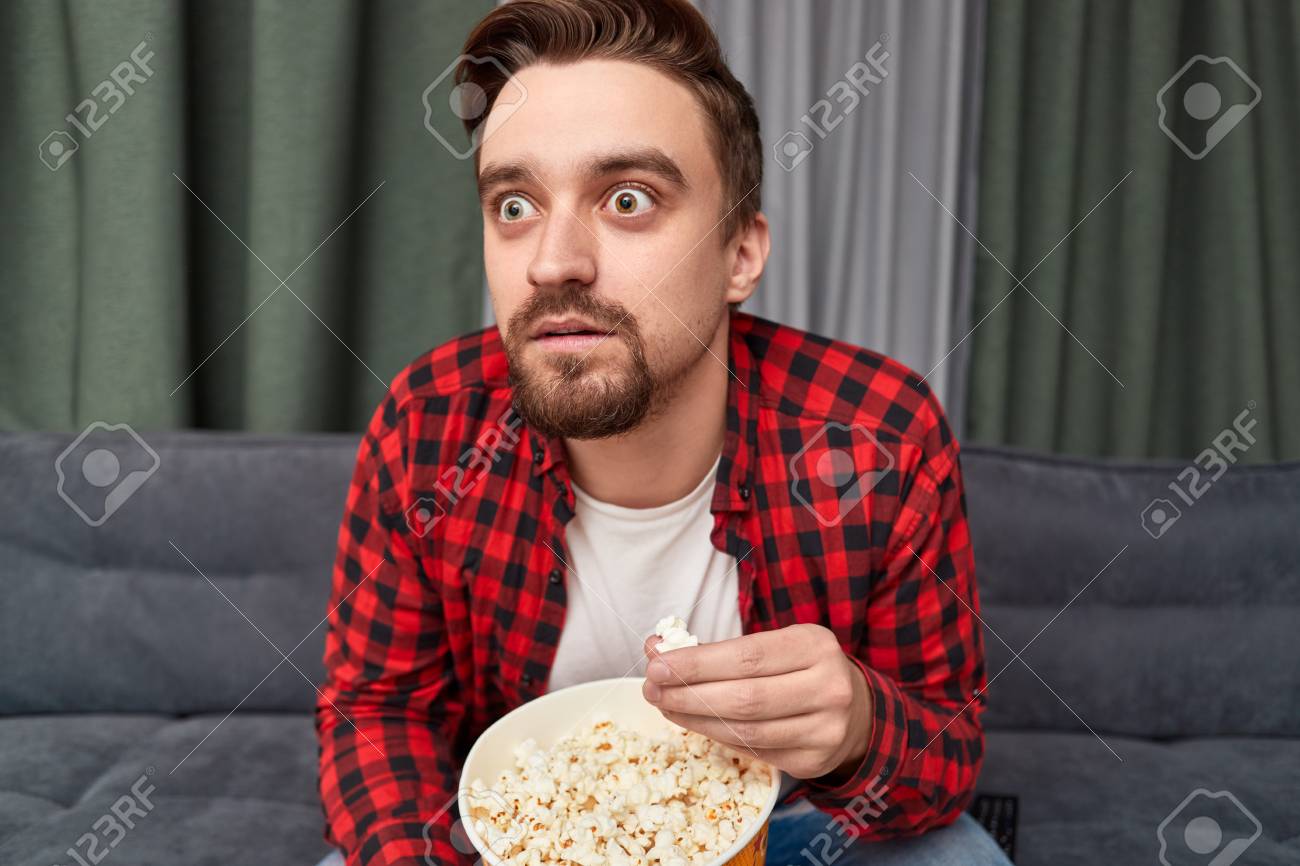121350405-shocked-man-eating-popcorn-and-watching-movie.jpg